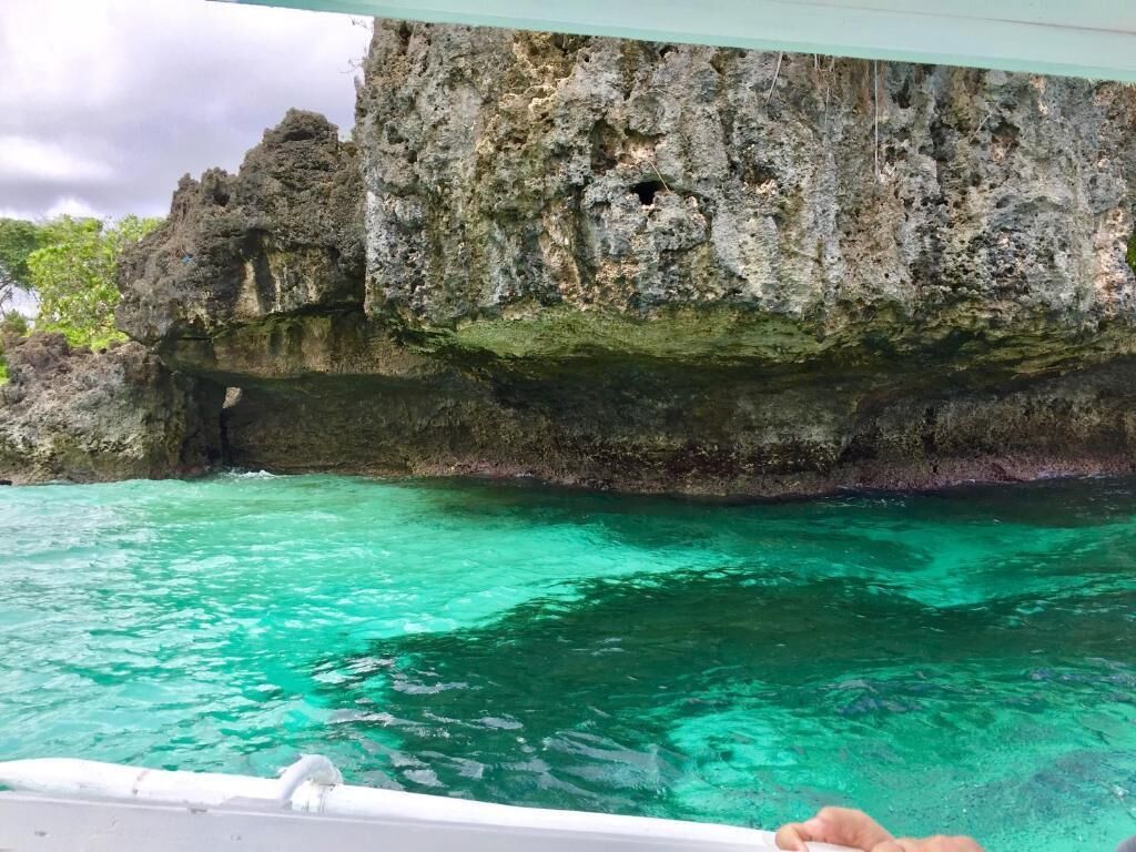 Una embarcación cerca de una costa rocosa con aguas turquesas cristalinas.