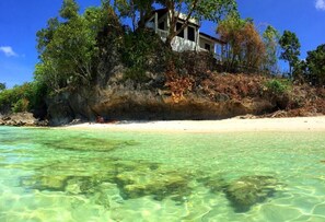 A beachfront property with clear water, a sandy beach, and a building surrounded by trees. - Casa Amihan (Anda)