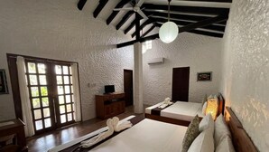 A room with two beds, a wooden desk, a wardrobe, and a large window with curtains. - Casa Amihan (Anda)