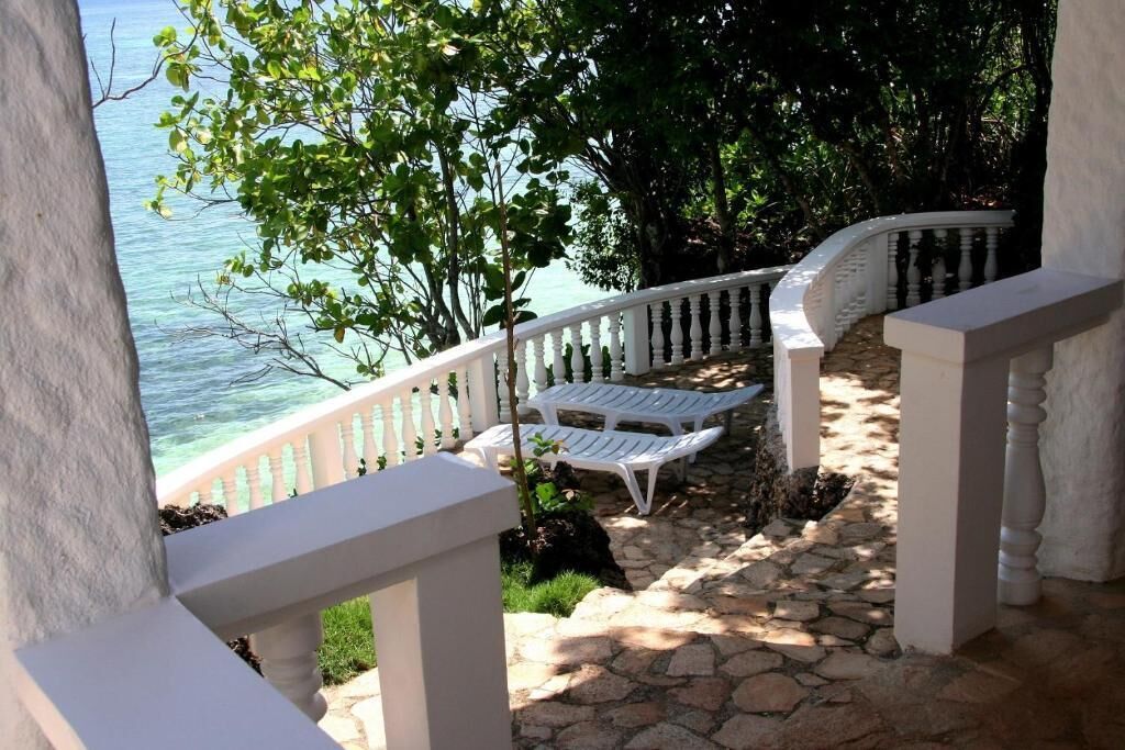A stone pathway leading to a white railing overlooking a body of water.