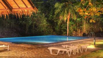 Una piscina al aire libre, sillones reclinables de piscina