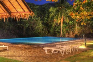 A swimming pool with lounge chairs and a thatched-roof structure. - Casa Amihan (Anda)