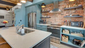 Una cocina moderna con una isla central, electrodomésticos de acero inoxidable y una pared de ladrillo decorativa.