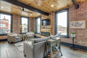 A modern living room with a fireplace, large windows, and a view of the city.