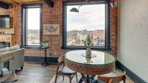 Una habitación acogedora con una mesa redonda de cristal, un sofá cómodo y un ventanal que ofrece vistas a edificios y una calle.