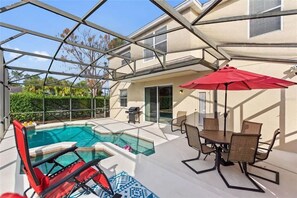 A pool area with a glass enclosure, a dining table with chairs, and a red umbrella. - Large pool home with spa - Gated West Haven Resort (Davenport)