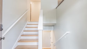 Un escalier avec des rampes blanches et des marches en bois menant à un palier.