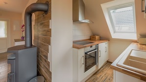A modern kitchen with a wood-burning stove, a window, and an oven.