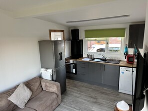 A compact kitchen with a refrigerator, oven, sink, and a window with a view of the outside. - Stunning 1-bed Chalet in Mablethorpe (Mablethorpe)