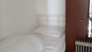 A small, single-bed room with a wooden floor, a radiator, and a wooden door. - Chalet Retreat in Mablethorpe (Mablethorpe)
