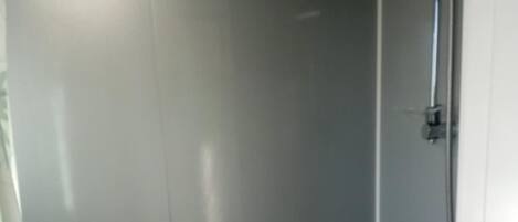 Cabina de ducha con puerta de cristal y ducha de mano.