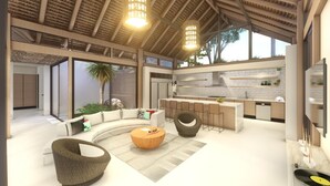 Um interior moderno com um sofá curvo, uma mesa de centro redonda de madeira e uma área de cozinha com revestimento de tijolos e banquetas.