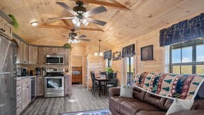 Ein gemütliches Blockhaus-Interieur mit Holzwänden, einer Küchenzeile, einem Essbereich und einem Wohnzimmer mit einer braunen Ledersofa.