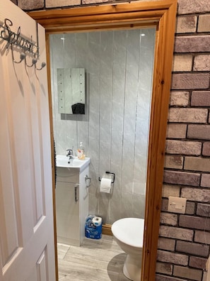 A small bathroom with a toilet, a sink, and a mirror. - Lovely 1-bed Chalet in Mablethorpe (Mablethorpe)