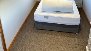 A single bed with a headboard, a bedside table, a nightstand, and a window with a view of greenery outside. - Lovely 1-bed Chalet in Mablethorpe (Mablethorpe)