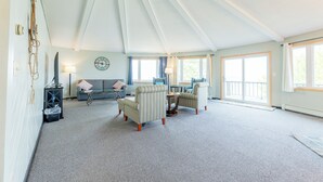 A spacious living room with a high ceiling, a large window, and a cozy seating area. - Your Superior Vacation Destination  (Ontonagon)