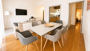 A modern living room with a dining table, grey woven chairs, a ceiling fan, a flat-screen TV, and a sofa. - Lumina Hidden Terrace - Charming Family Apartment in the Heart of Perugia (Perugia)