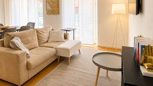 A modern living room with a beige sofa, a small round table, and a floor lamp. - Lumina Hidden Terrace - Charming Family Apartment in the Heart of Perugia (Perugia)
