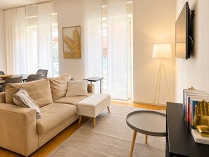 A modern living room with a beige sofa, a small round table, and a floor lamp.