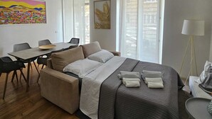 A modern hotel room with a bed, a dining area, and a ceiling fan. - Lumina Hidden Terrace - Charming Family Apartment in the Heart of Perugia (Perugia)