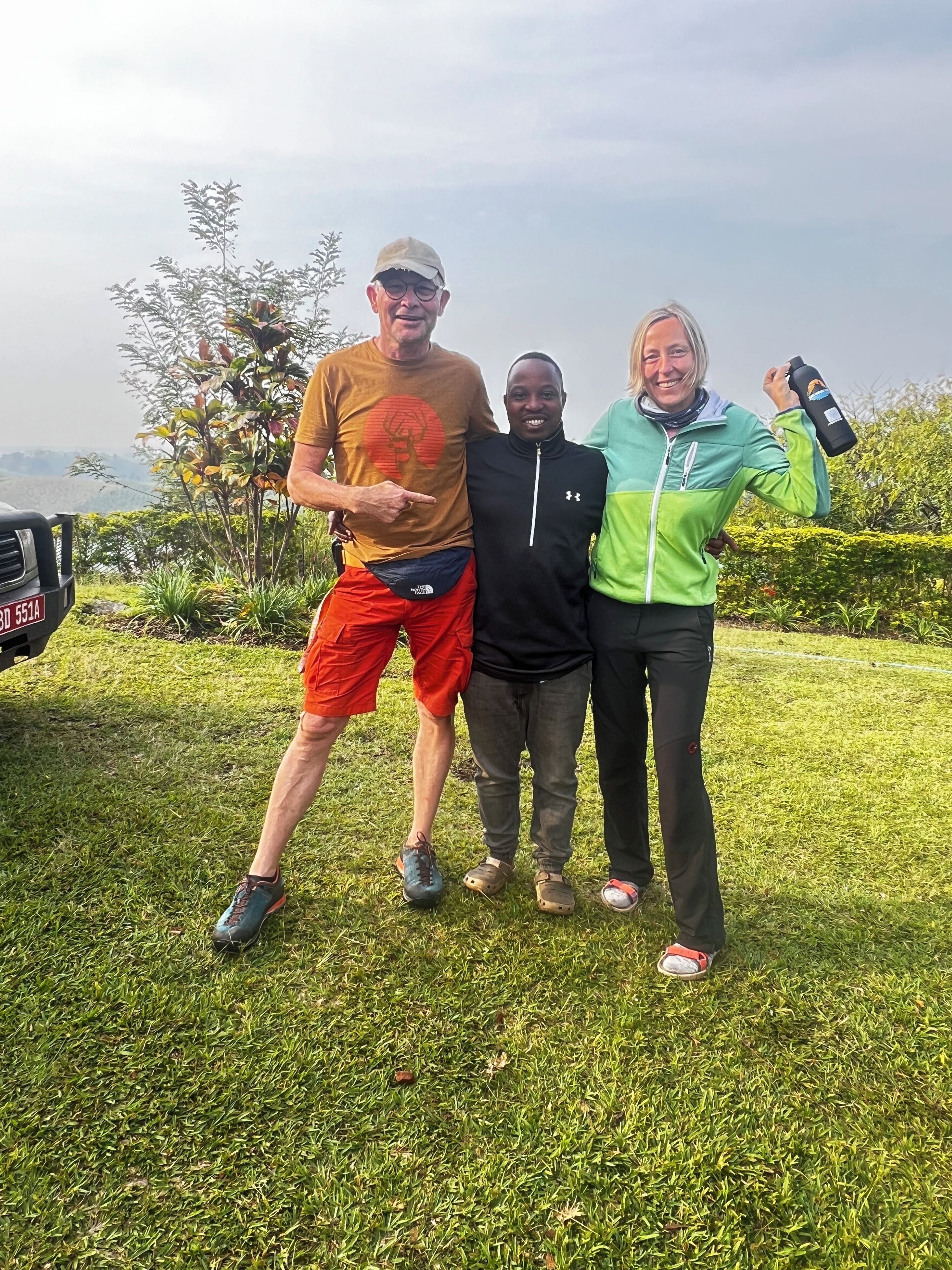 Tres personas de pie al aire libre, rodeadas de hierba y vegetación.