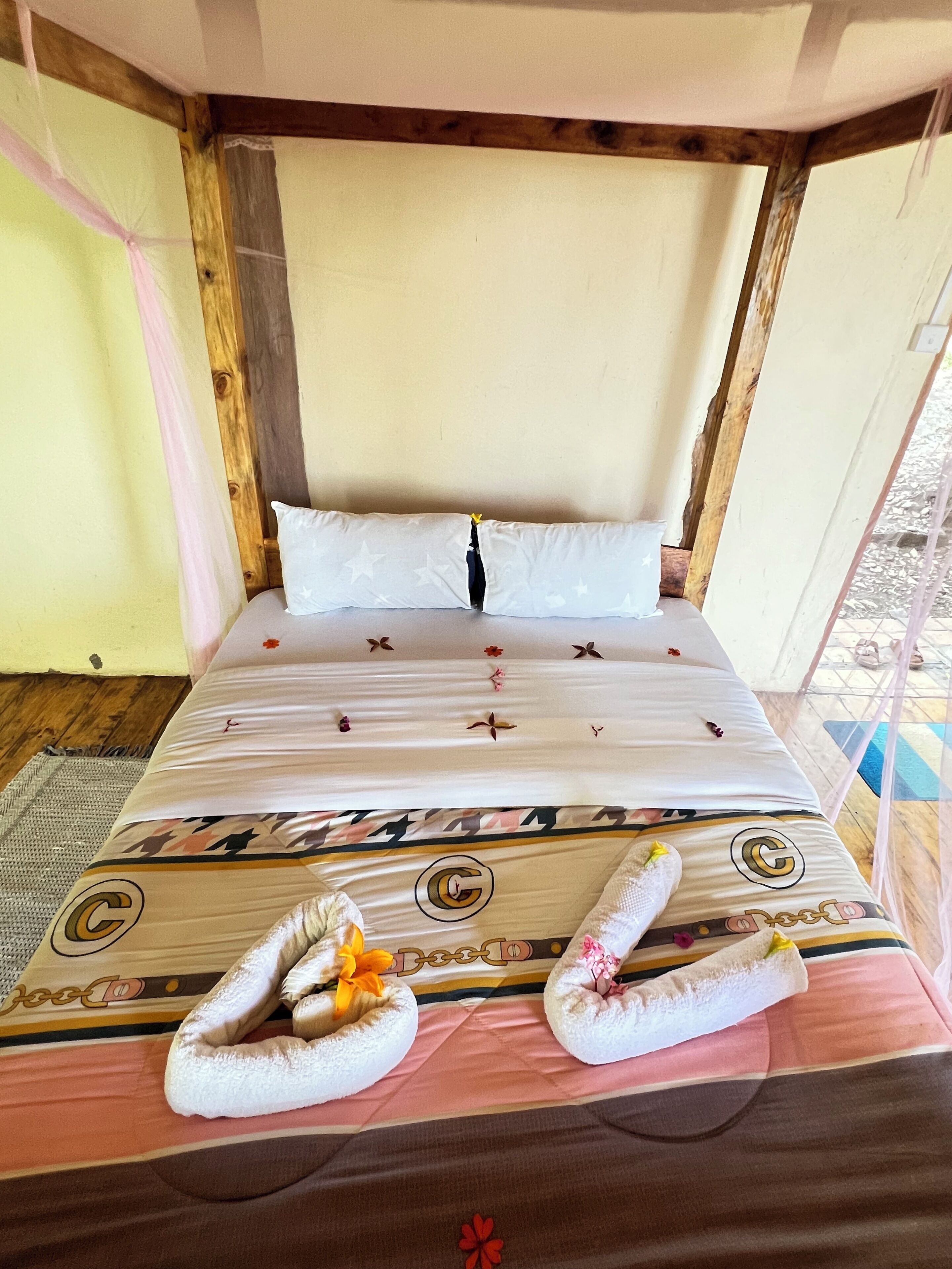 A bed with a patterned bedspread, two pillows, and two towels with flowers.