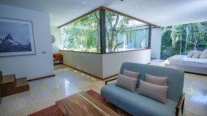 Una sala de estar moderna con un ventanal grande, un sofá azul y una mesa de centro de madera.