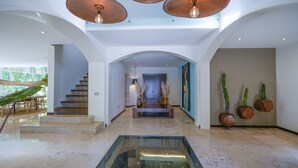 Un hall espacioso con suelo de mármol, una fuente con fondo de cristal y una escalera.