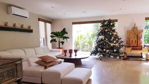 Un salón amplio con un sofá blanco, una mesa redonda de centro y un gran árbol de Navidad.