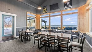 Un restaurant doté d’une grande salle à manger, de tables et de chaises en bois, et de grandes fenêtres offrant une vue sur la plage.