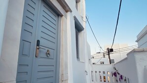 A narrow white-walled corridor with a blue door and a stone-patterned floor. - Villa Loom Mykonos Town (Mykonos)