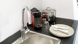 A compact kitchen with a modern sink, a pot on the stove, and a plate with cutlery. - Villa Loom Mykonos Town (Mykonos)