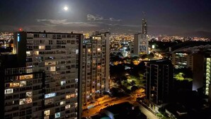 A nighttime cityscape with illuminated buildings and a prominent tower.