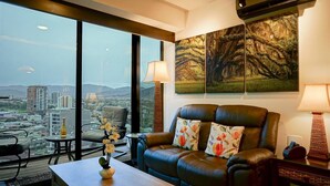 A modern living room with a leather sofa, a coffee table, and a view of a cityscape through large windows.