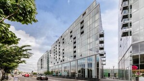 A modern building with a glass facade, multiple floors, and a flat roof. - Zedwell Greenwich (London)