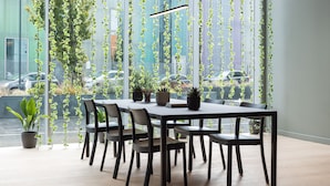 A modern dining area with a rectangular table, six chairs, and hanging plants. - Zedwell Greenwich (London)