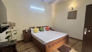 Une chambre à coucher avec un lit en bois, une table de chevet, une lampe, un luminaire fixé au mur et un tableau encadré.