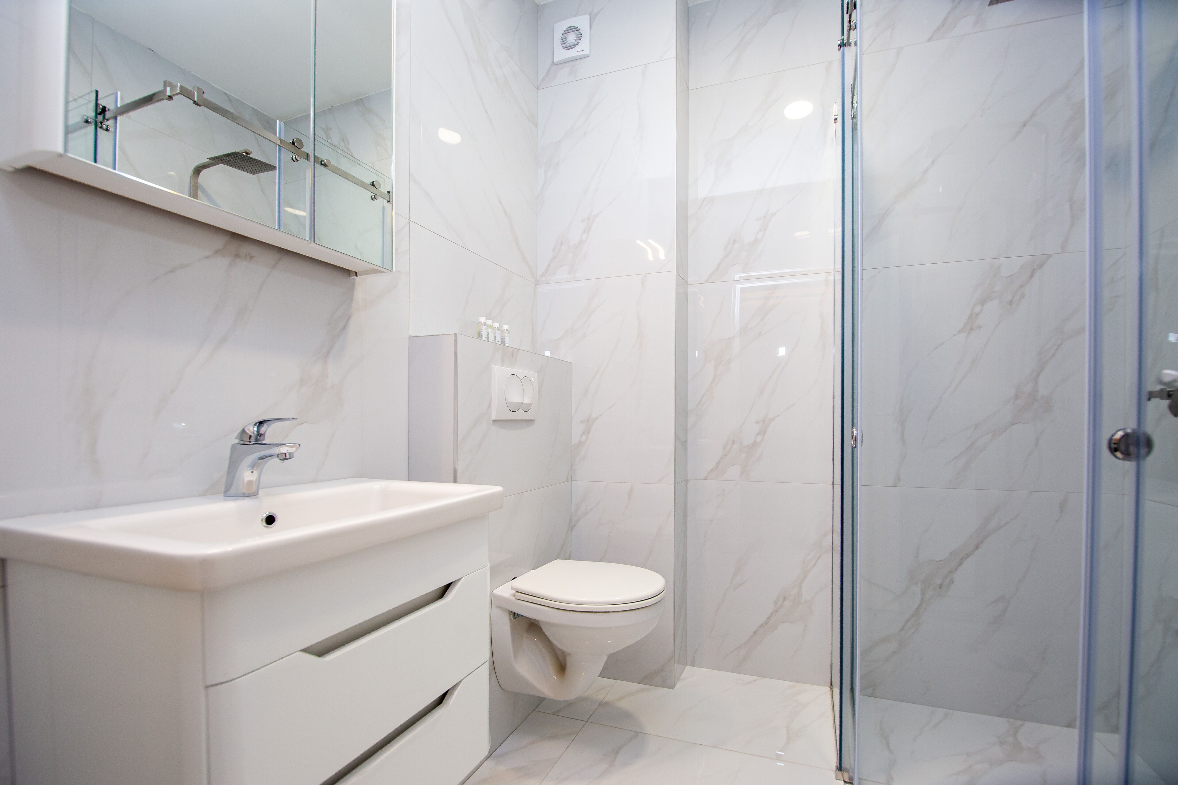 A modern bathroom with a glass shower enclosure, a white sink, and a toilet.