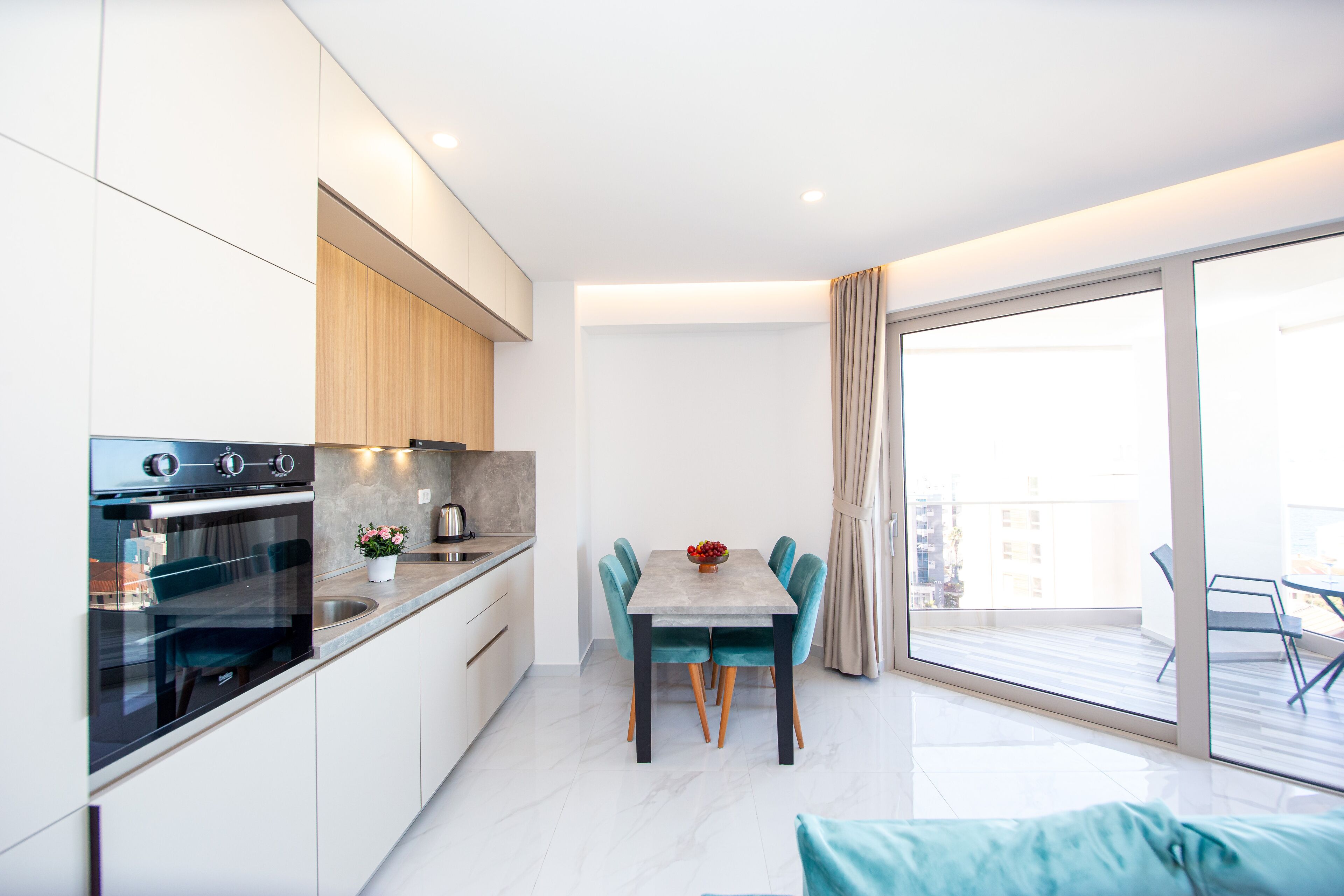 Une cuisine moderne avec un coin repas, une grande fenêtre et un balcon.