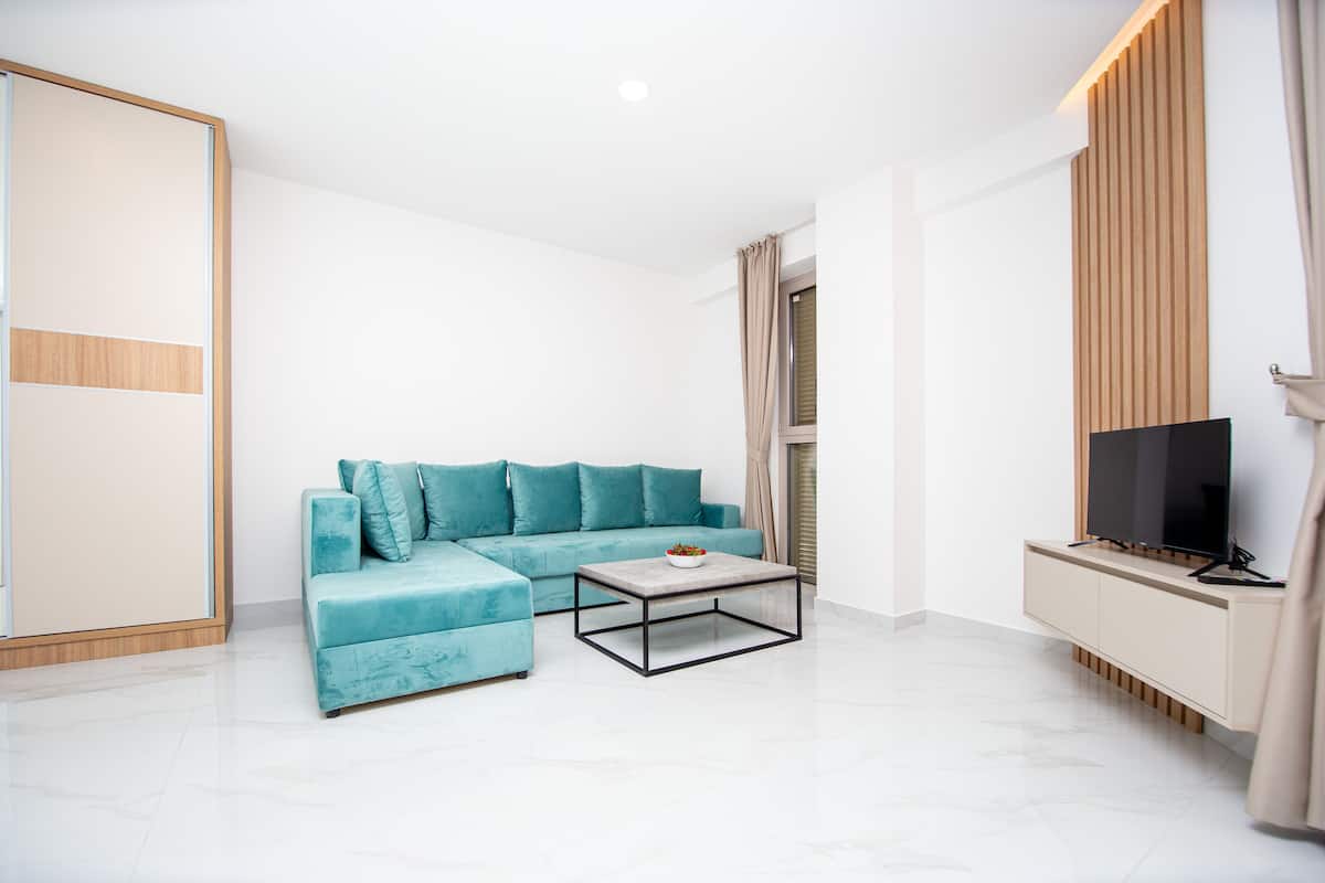 A modern living room with a teal sofa, a coffee table, and a TV on a wooden cabinet.