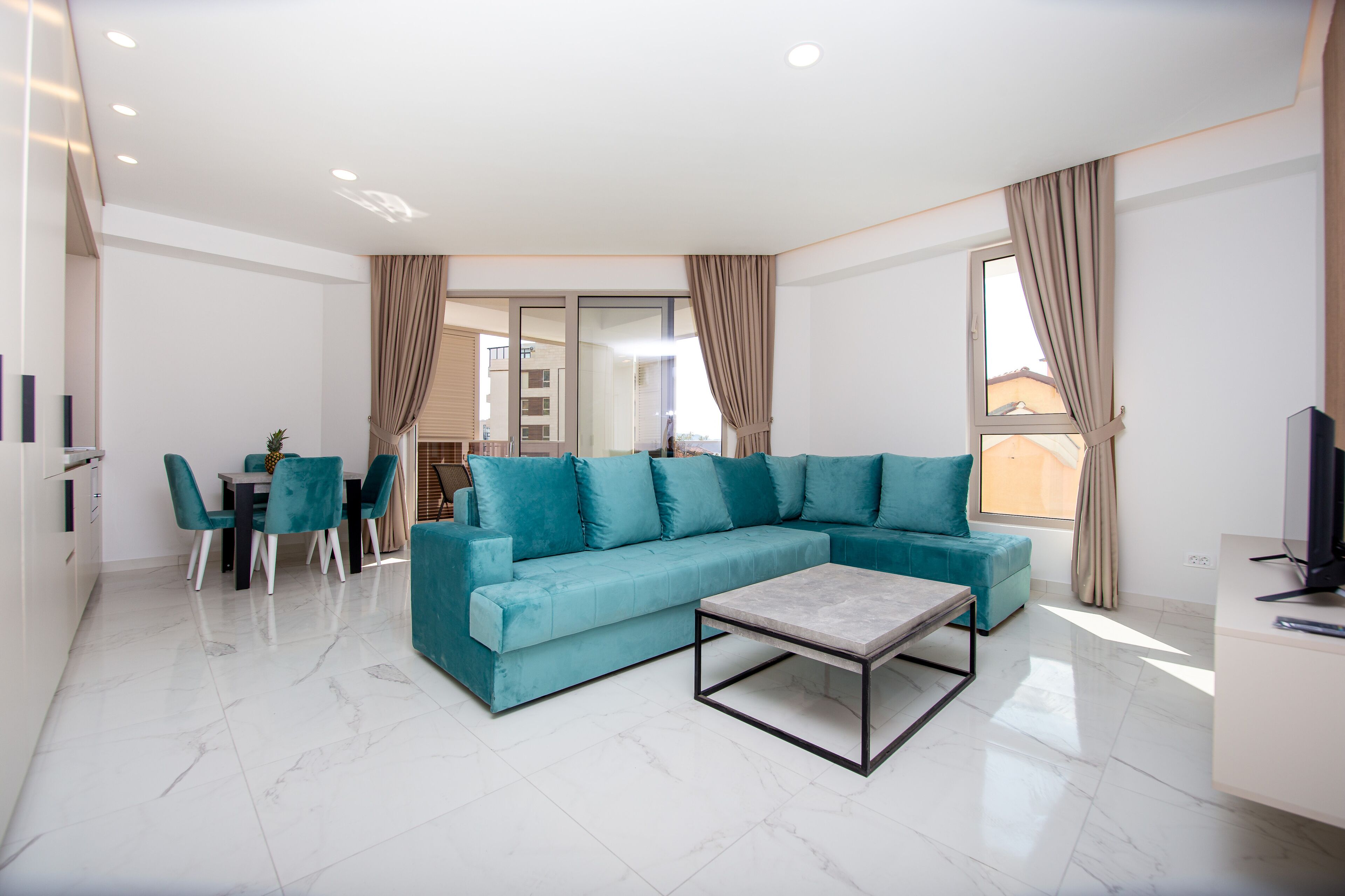 Una sala de estar moderna con un sofá color turquesa, una mesa de centro y un comedor con sillas.