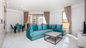Una sala de estar moderna con un sofá color turquesa, una mesa de centro y un comedor con sillas.