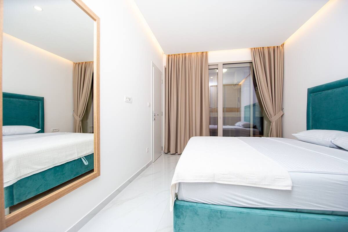 A hotel room with two beds, a large mirror, and a sliding glass door leading to a balcony.