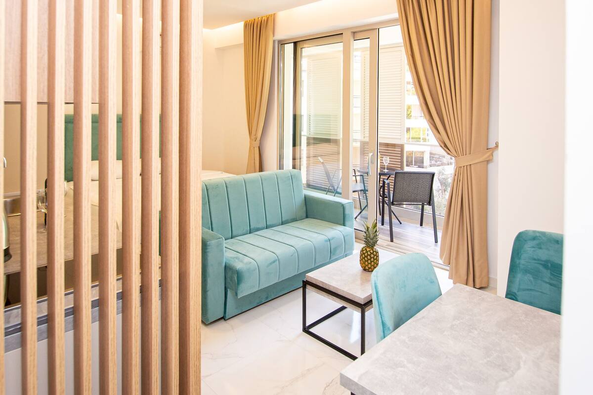 A modern living room with a sofa, a dining table, and a view of the outside.