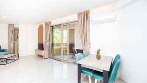 A modern living room with a dining area, large sliding glass doors, and a flat-screen TV. - IN Property Apartments (Becici)