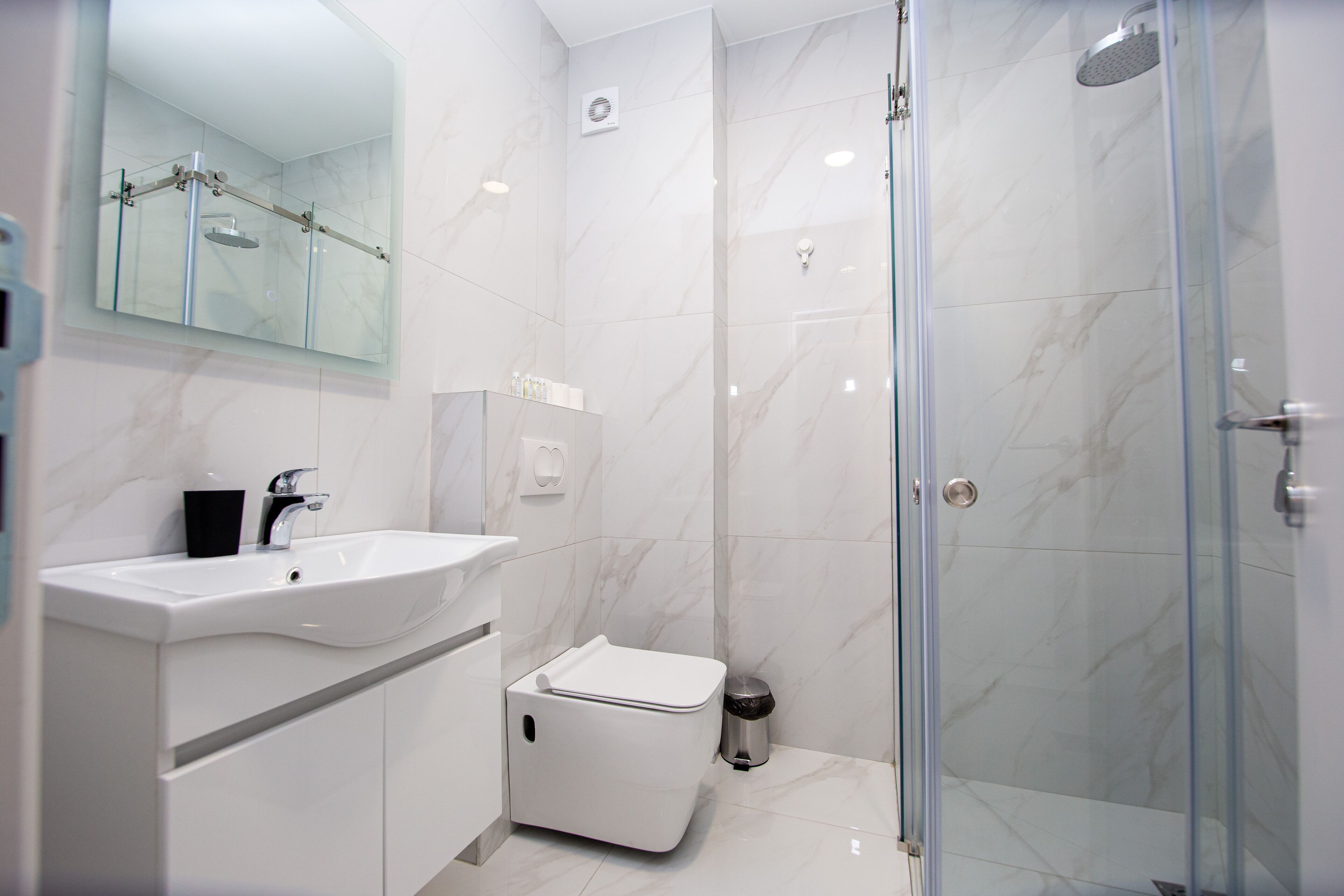 Une salle de bain moderne avec une douche à parois de verre, un lavabo blanc et des toilettes.