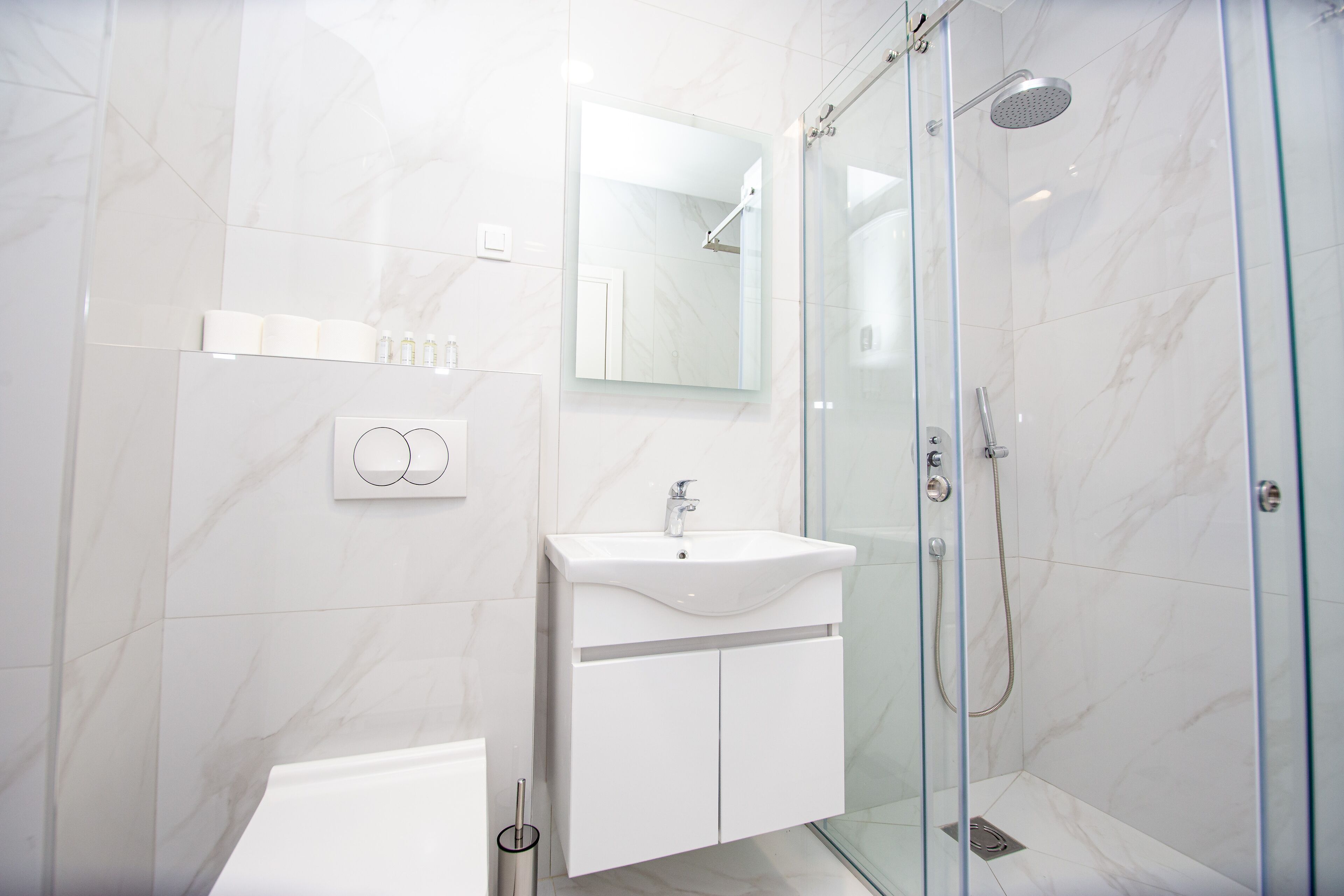 A modern bathroom with a glass-enclosed shower, a white sink, and a mirror above it.