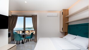 A hotel room with a bed, a desk, a chair, and a view of the sea. - IN Property Apartments (Becici)