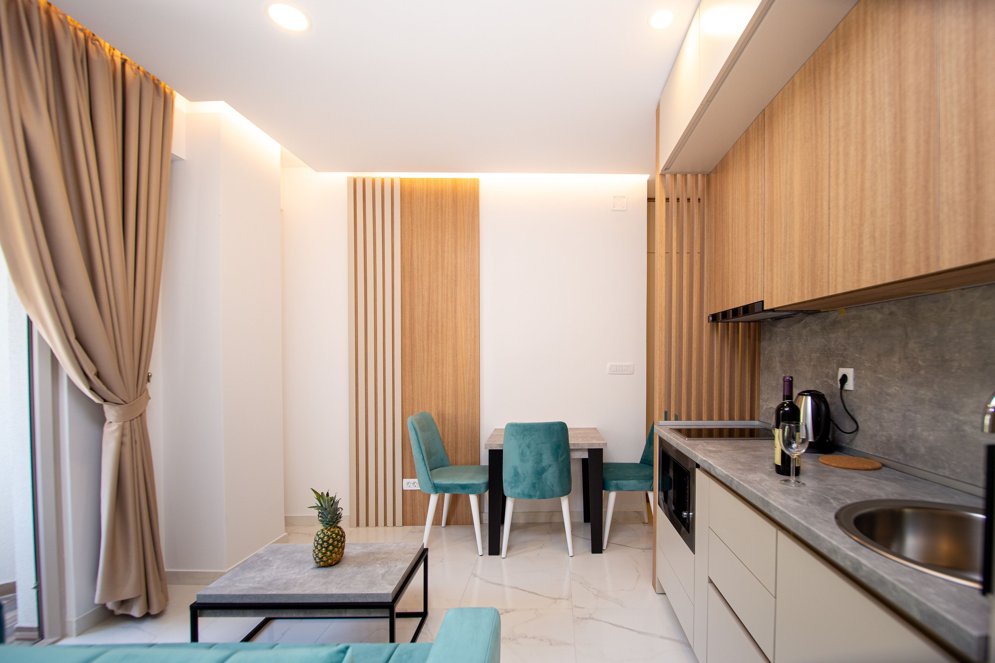 A modern kitchen with a dining area, wooden cabinets, and a stainless steel sink.