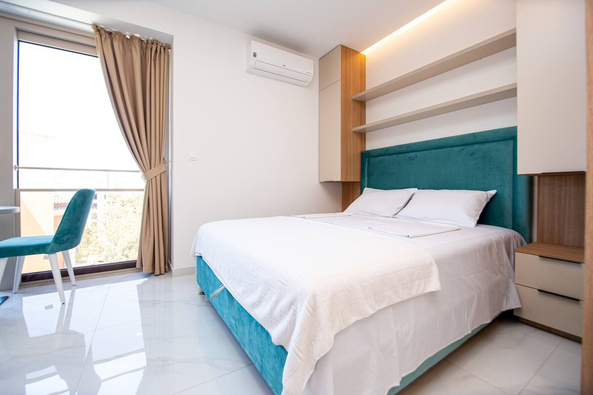 A modern bedroom with a bed, a chair, and a balcony view.